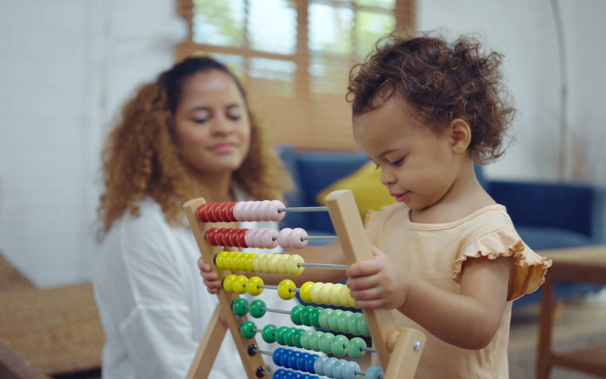 Mother and daughter are doing play a toy and having fun in living room.